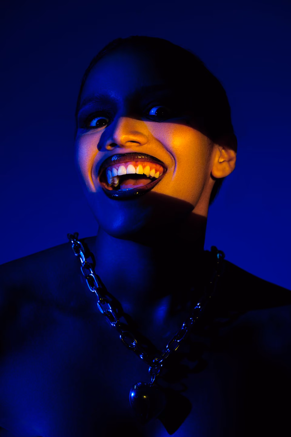 A woman laughing in blue light, a stripe of warm light over her face